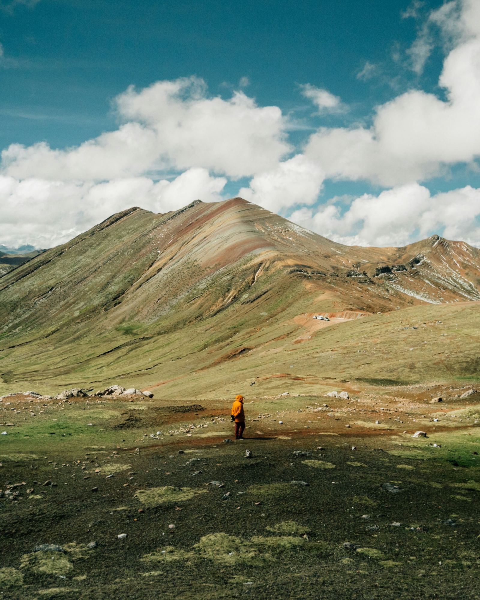 A lone walker beneath a striped mountain