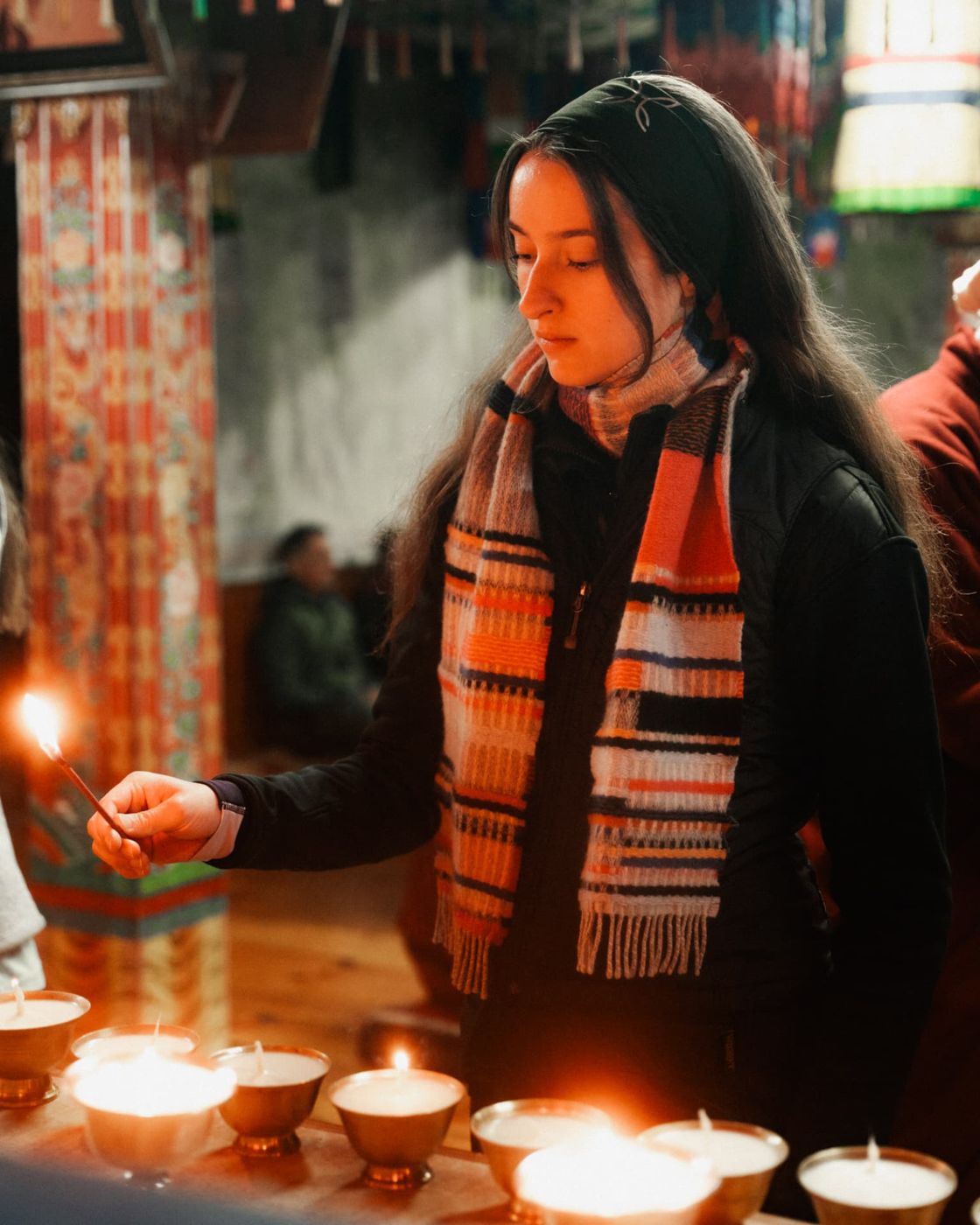 A participant lighting butter lamps in a temple