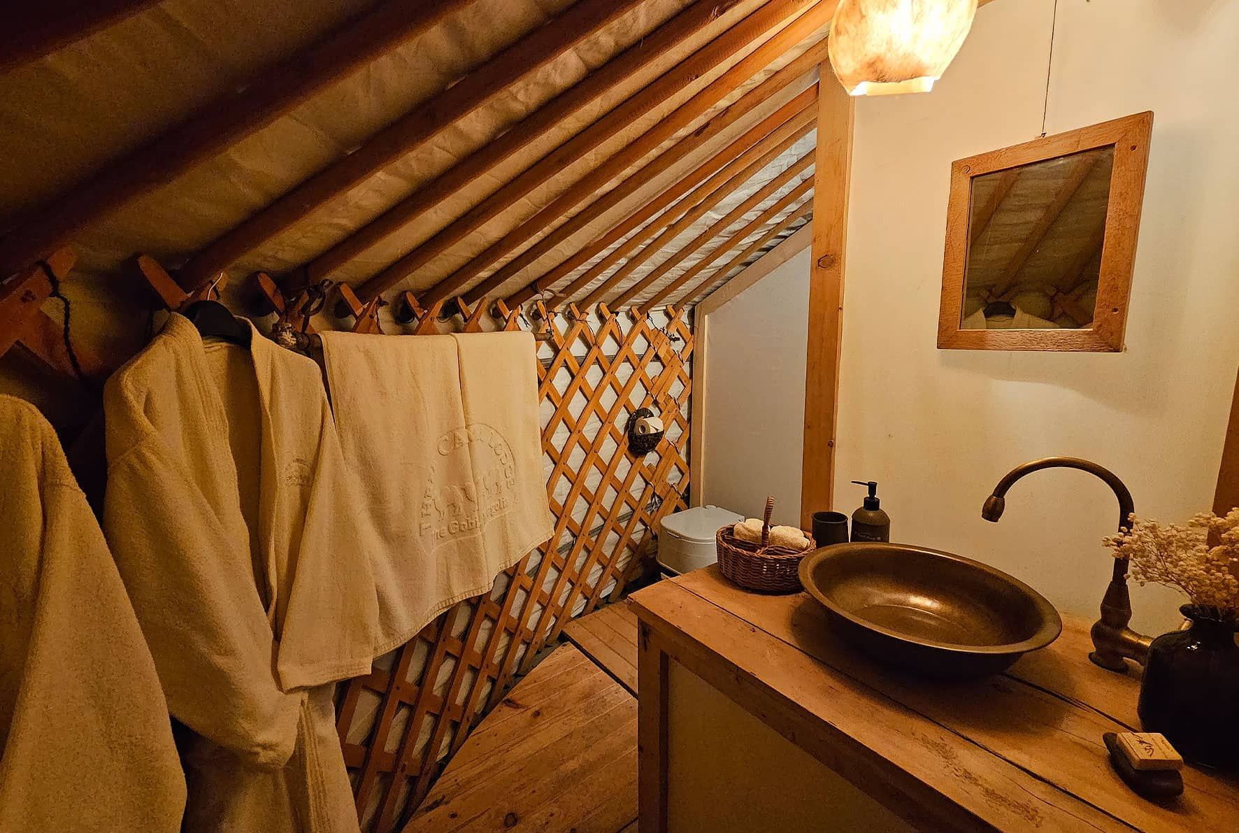The washroom inside a ger, with robes and a copper basin