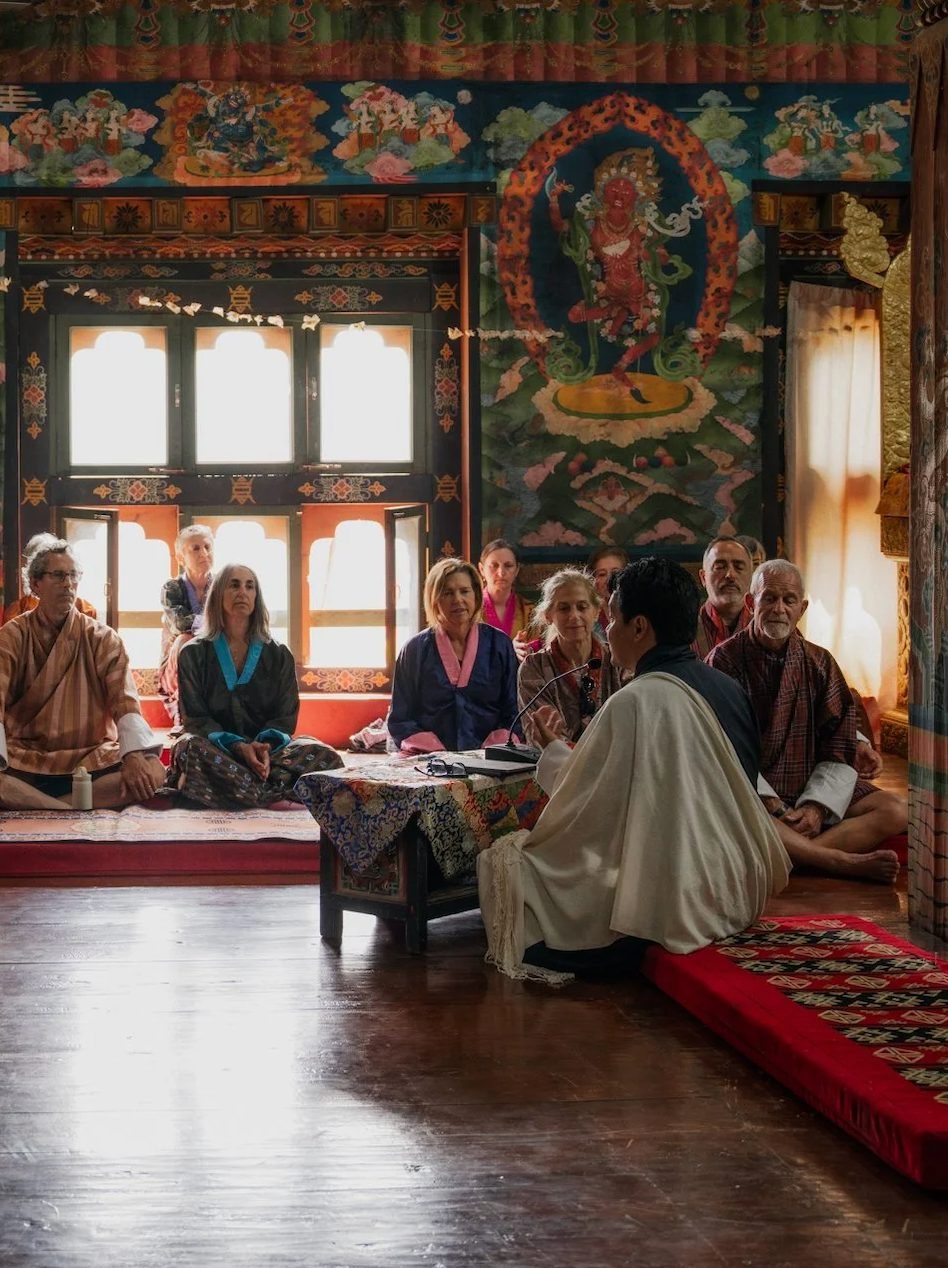 Travellers seated for a teaching in a painted Bhutanese temple