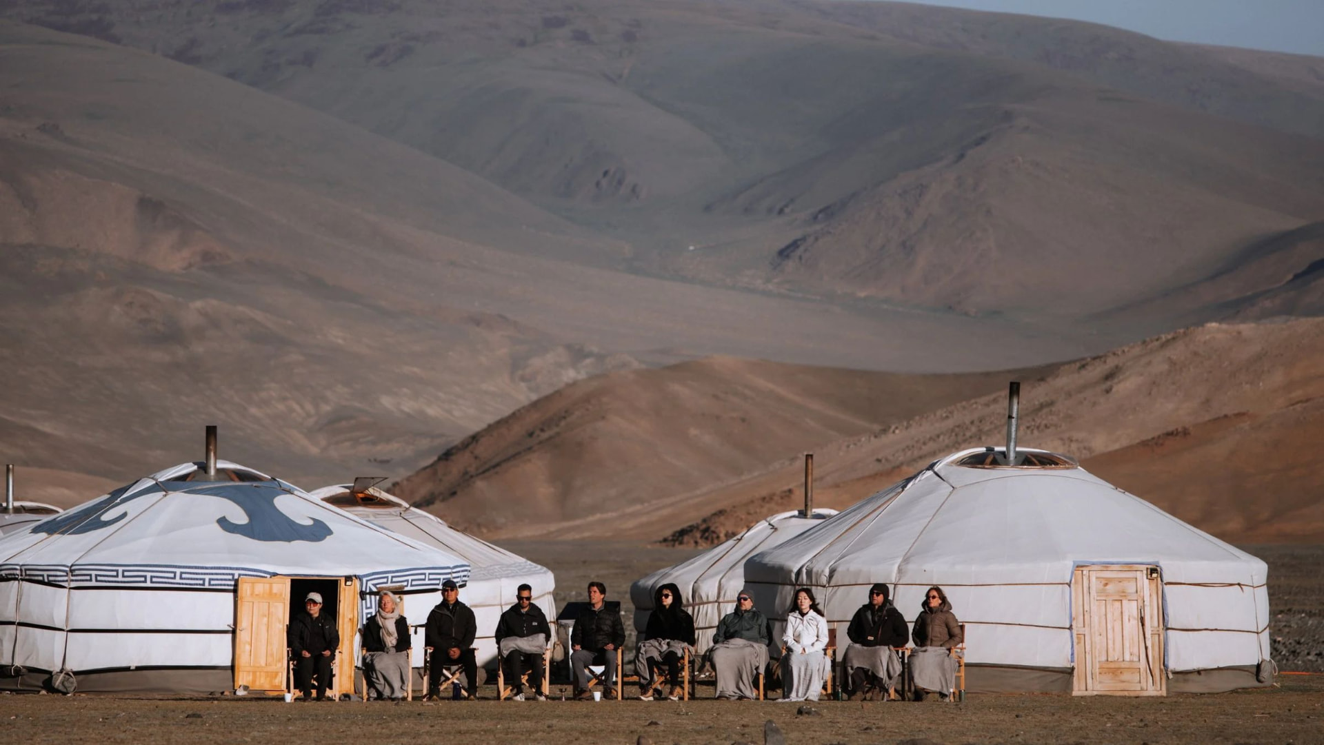 The group sitting in silence in front of the gers