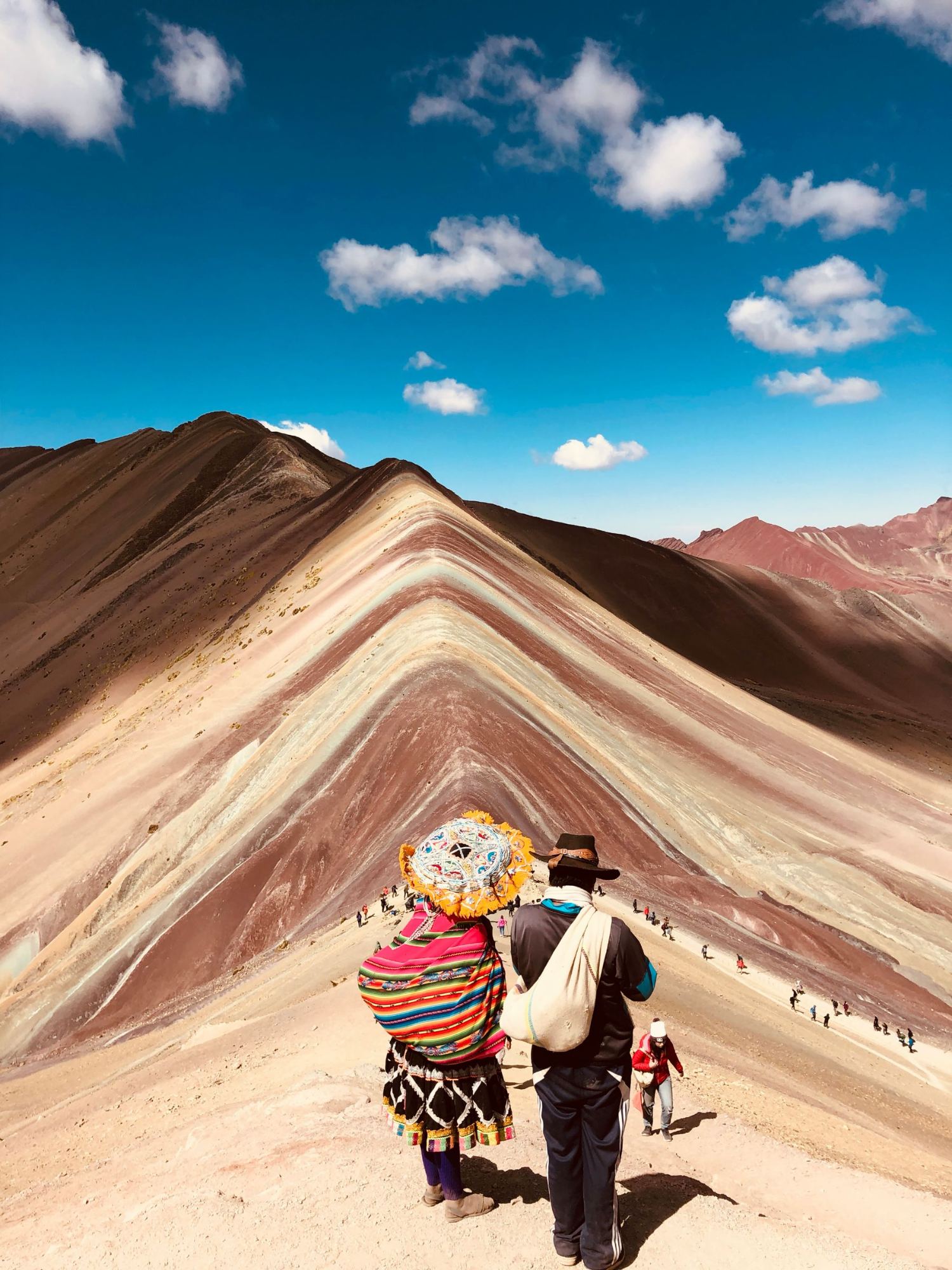 An Andean couple looking out over Rainbow Mountain