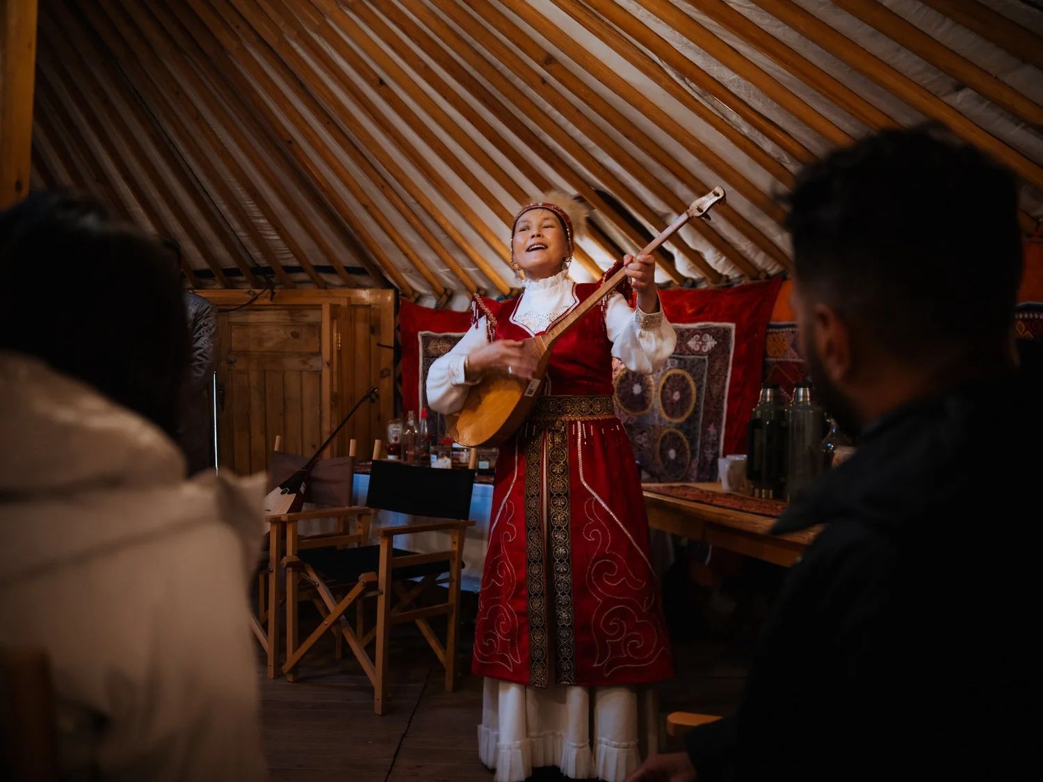 A woman singing with a dombra inside a ger