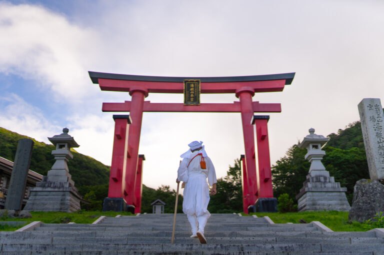 Yamabushi passing beneath a torii gate