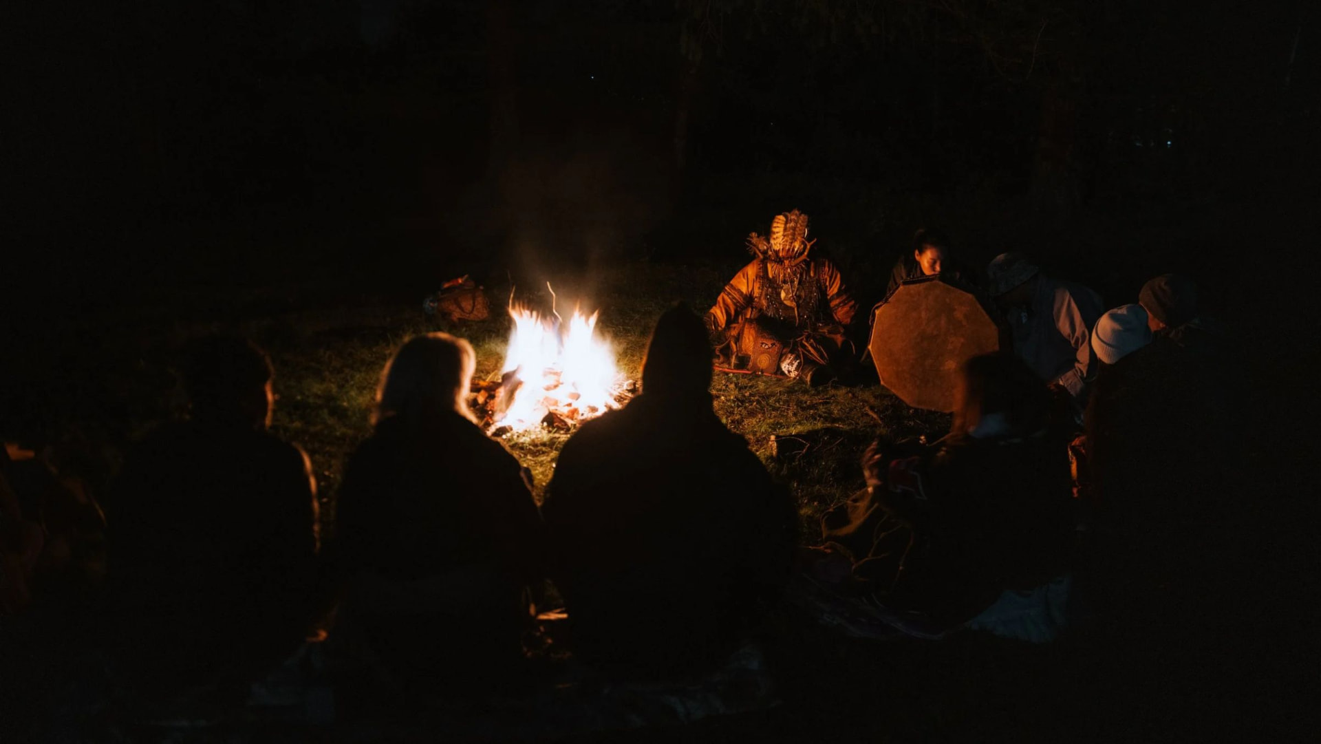 The group gathered around the fire as the shaman's drum begins