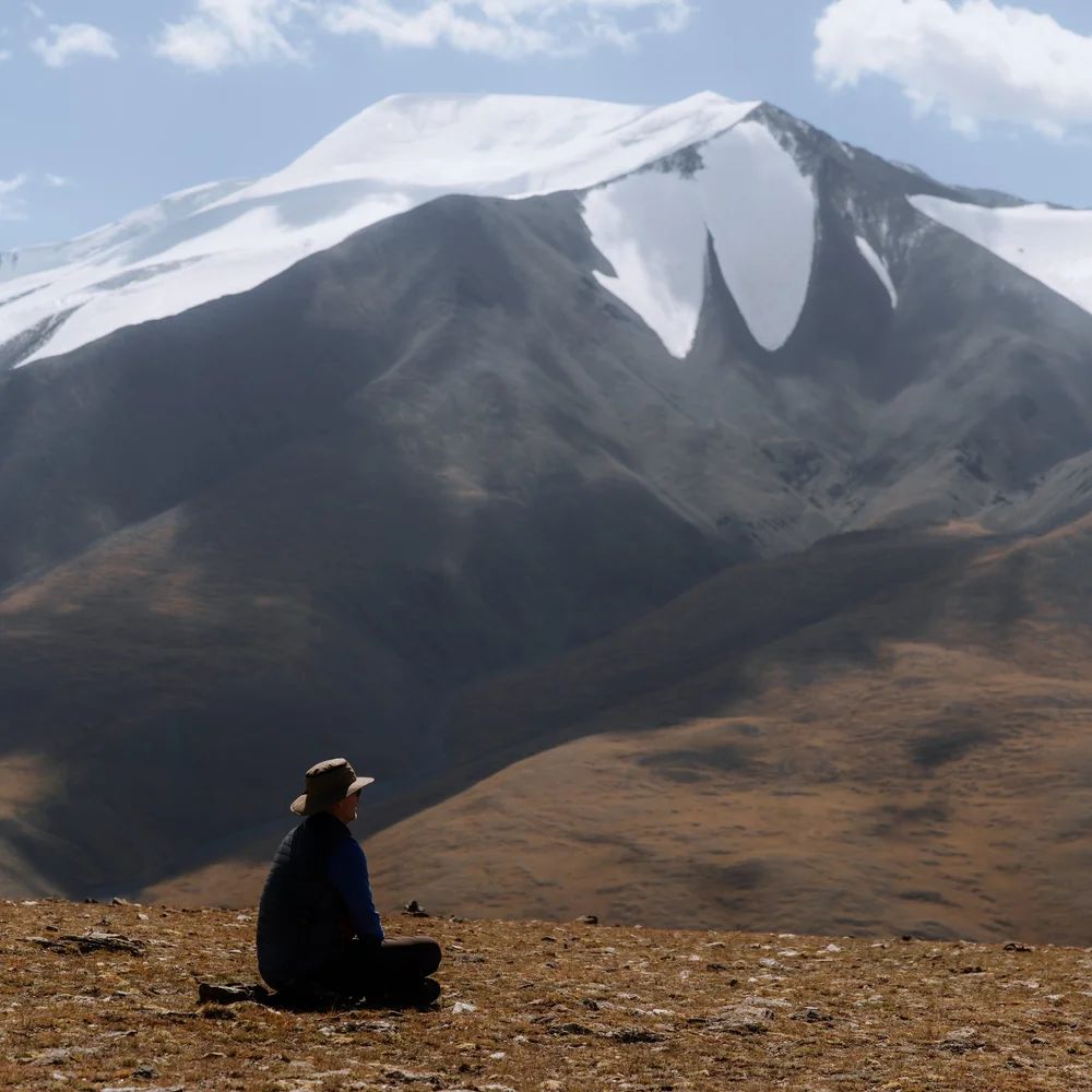 A traveler sitting before a snow-capped peak