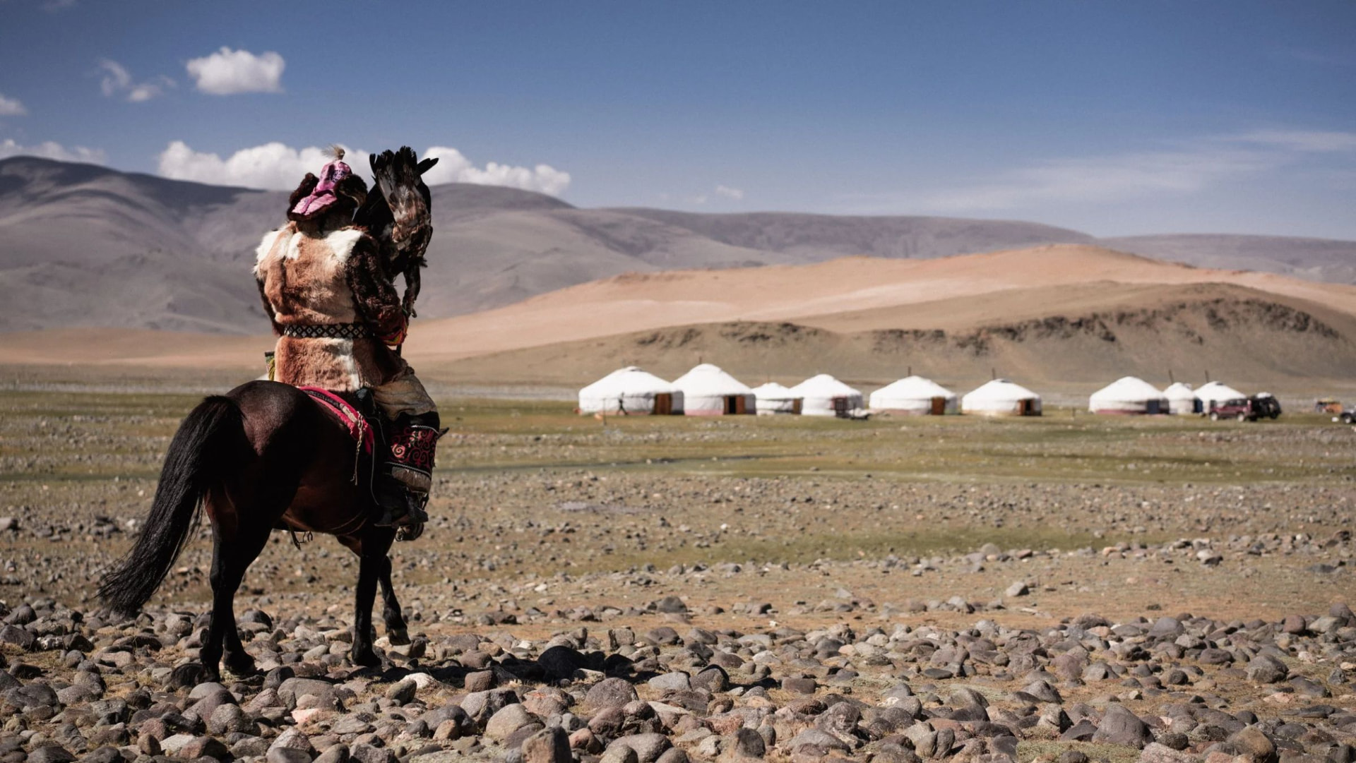An eagle hunter riding toward the ger camp