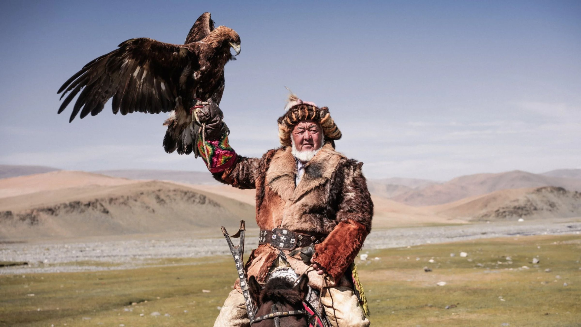 A Kazakh eagle hunter on horseback with his golden eagle