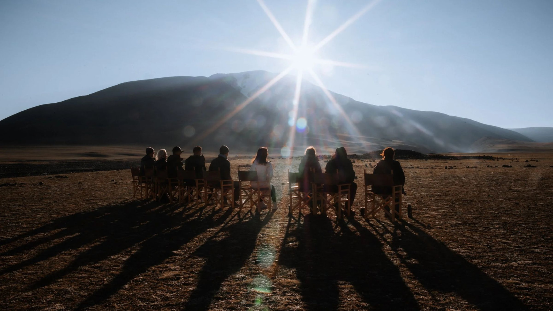 A group seated before a mountain as the sun breaks over it